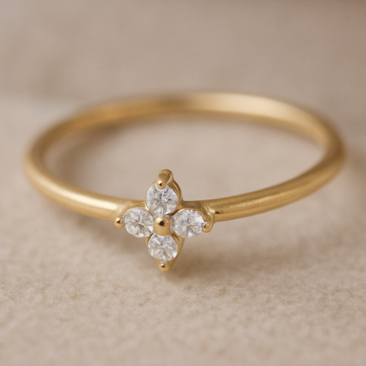Gold ring with a diamond flower design on a beige background